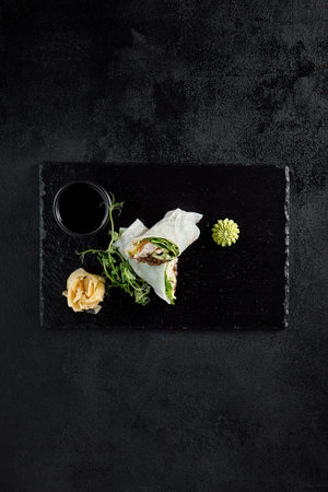 Chicken and wood mushroom sprint roll in rice paper with pea sprouts, top view on a black background.の写真素材
