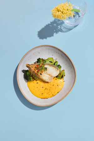Halibut steak with pumpkin puree and broccoli, ideal for a vibrant summer menu in a high-end eatery.の写真素材