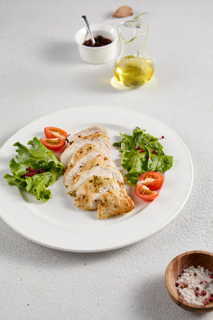 Grilled chicken breast with vibrant salad garnish on a minimalistic white setup, perfect for clean eating and diet concepts.の写真素材