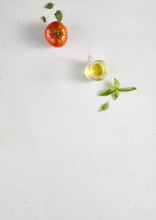 Minimalist food background with an empty white textured table, tomato, and olive oil, top view with ample copy space. Perfect for recipe books and cooking guides.の写真素材
