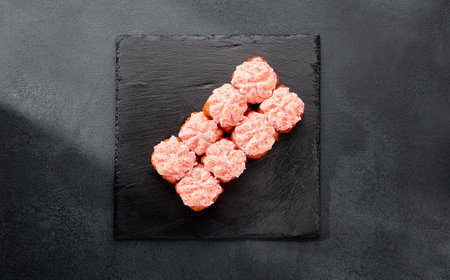 Sushi roll with tobiko caviar, topped with a creamy cheese cap and more caviar; a luxurious bite with a rich texture.の写真素材