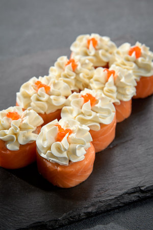 Deluxe Philadelphia rolls wrapped in salmon and topped with a dollop of cream cheese, a luxurious sushi treat.の写真素材