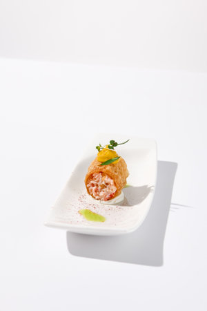 Crunchy crabmeat cannoli on a sleek white dish with a citrus accent, perfect for refined appetizers and modern cuisine.の写真素材