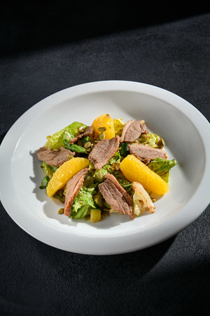 Duck and orange salad closeup with walnuts, on a bed of mixed greens, drizzled with a balsamic reduction.の写真素材
