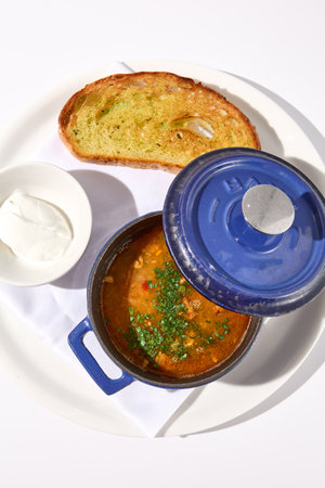 Top view of aromatic fish soup with a smoky touch, served in a cobalt blue pot with croutons and sour cream, isolated on white.の写真素材