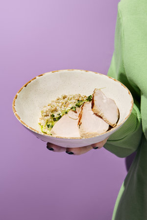 Hand-Held Bowl of Green Buckwheat in Coconut Sauce with Sous-Vide Turkey. Person Presenting a Healthy, Home-Cooked Meal.の写真素材