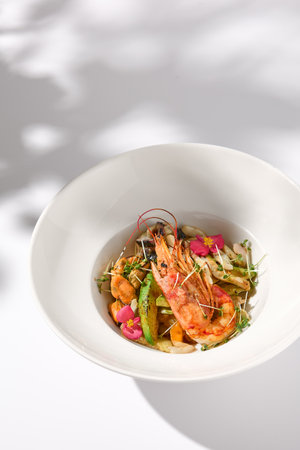 Zucchini Seafood SautÃ© with Shrimp and Elegant Floral Garnish on Shadowed White.の写真素材