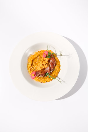Top view of duck breast with pumpkin risotto on white, ideal for autumn menu promotions and food blogging.の写真素材