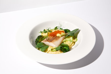 Cod Fillet with Red Caviar and Zucchini and Broccoli Garnish on White, an Elegant Dish for Fine Dining.の写真素材