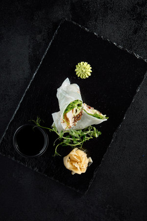 Chicken and wood mushroom sprint roll in rice paper with pea sprouts, top view on a black background.の写真素材