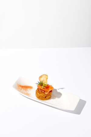 Elegant salmon profiterole garnished with dill on a minimalist white plate, ideal for gourmet finger food concept.の写真素材