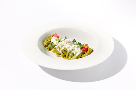 Pesto Pasta with Stracciatella Cheese Garnished with Pine Nuts and Edible Flowers, Perfect for Modern Italian Cuisine.の写真素材