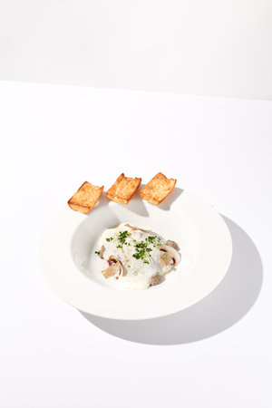 Creamy porcini mushroom soup with cheese espuma and croutons, elegantly presented.の写真素材