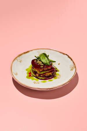 Beetroot mille-feuille with pesto sauce on a chic plate against a coral pink backdrop, a delight for gourmet vegetarian cuisine.の写真素材