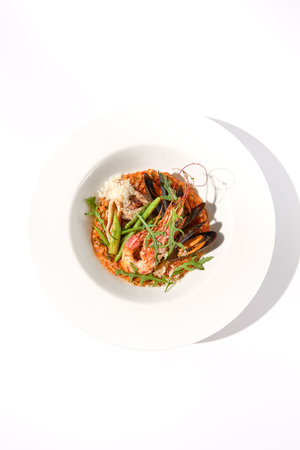 Top view of tomato risotto with seafood on white, suitable for Mediterranean diet and seafood cuisine showcases.の写真素材