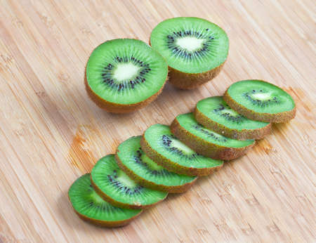 Fresh Slices of Kiwi on Wooden Cutting Board Backgroundの写真素材