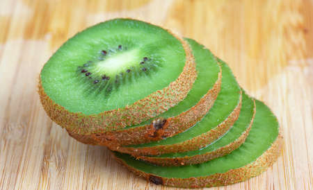 Fresh Slices of Kiwi on Wooden Cutting Board Backgroundの写真素材