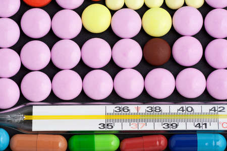 Pills and thermometer over dark backgroundの写真素材