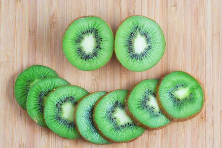 Fresh Slices of Kiwi on Wooden Cutting Board Backgroundの写真素材