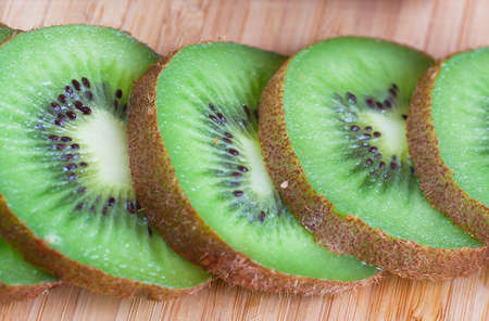 Fresh Slices of Kiwi on Wooden Cutting Board Backgroundの写真素材