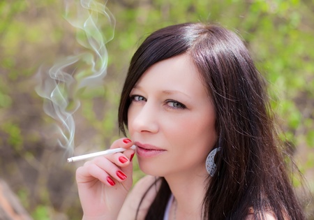 closeup of a pretty woman smoking at the streetの写真素材