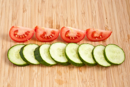 Cucumber and tomato on a wooden boardの写真素材