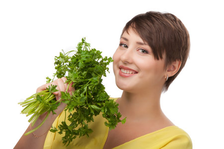 Young beautiful girl holding bunch of parsley near the faceの写真素材