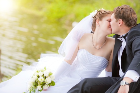 the newly married couple kissing in parkの写真素材