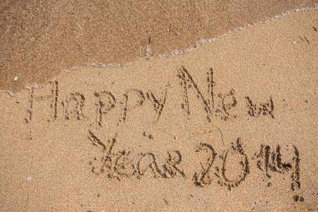 New Year 2014 is coming concept - inscription 2013 and 2014 on a beach sand, the wave is starting to...