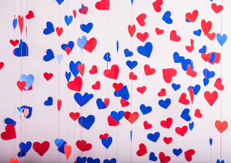 Background of red and blue paper hearts hanging on stringsの写真素材