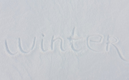 The word winter written with broken wooden sticks on snow backgroundの写真素材