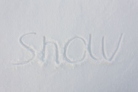The word snow written with broken wooden sticks on snow backgroundの写真素材