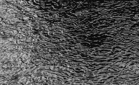 Rain on asphalt or tarmac road creating ripples, high contrast during autumn.