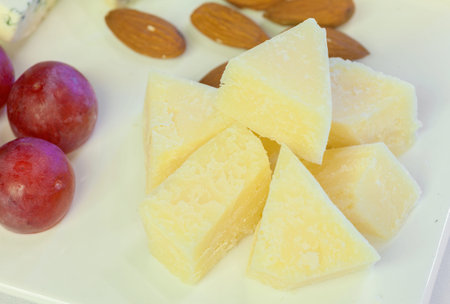 Parmesan cheese with grape on wooden board