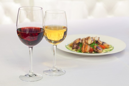 white and red wine in glasses on a background of foodの写真素材
