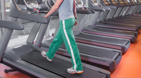 Fitness girl running on treadmill. Woman with muscular legs in gym