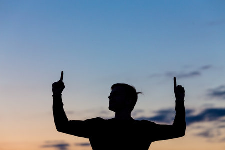 Silhouette of male celebrating with arm up towards the sunriseの写真素材