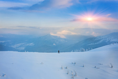 Couple skiing in a groomed curved double ski track with mountain summits and a characteristic cloud formation in the background in the norwegian mountains at easter.の写真素材