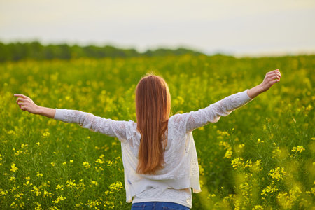 Joyful girl at yellow rape seed meadow