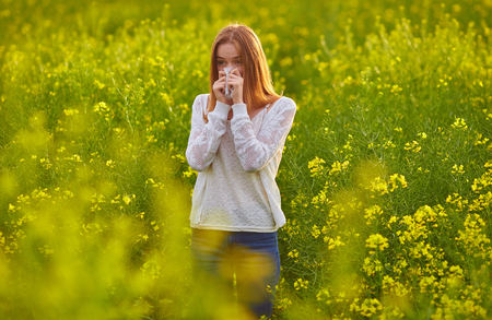 Pollen allergy, girl sneezing in a field of flowersの写真素材
