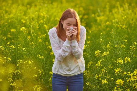Pollen allergy, girl sneezing in a field of flowersの写真素材