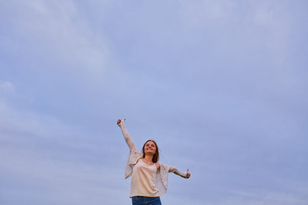 Girl with open arms on a green wheat field in the morningの写真素材