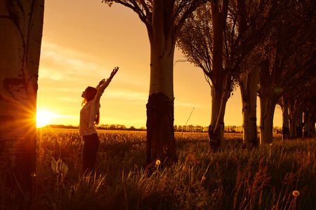 Girl with open arms on a green wheat field in the morningの写真素材