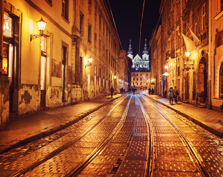 Mysterious narrow alley with lanterns in an old European city at nightの写真素材