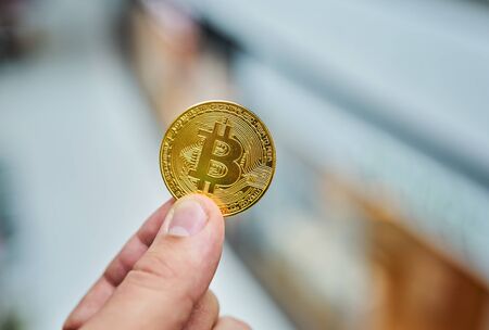 man's hand holding golden Bitcoin on Bitcoin mining backgroundの写真素材