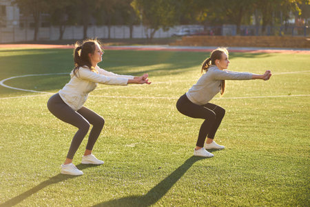 two young sports girls doing gymnastics in the morning on the green grass. open air, dawn, fitness, health, sports.の写真素材