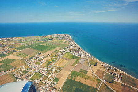 The plane is flying over the island of Cyprus. Airplane wing in flight from window.の写真素材