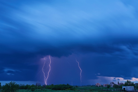 Massive colorful cloud to ground crazy skies lightning bolts hitting the horizon of city lights.の写真素材