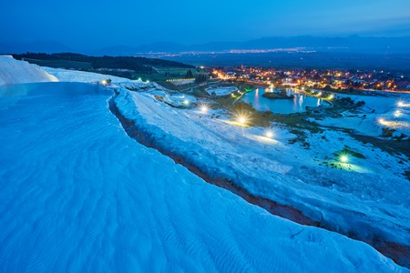 Pamukkale - amazing natural site with white terraces of travertine in Denizli Province, Turkey. Aerial view town of Pamukkale at foot of hot springs and neighborhood in evening.の写真素材