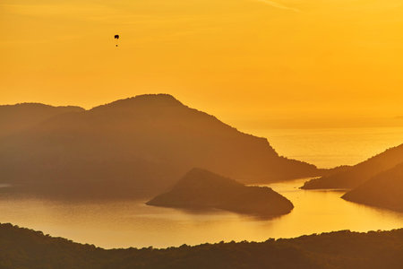 An unidentified paraglider flying at sunset over lagoon in Oludeniz, Turkey